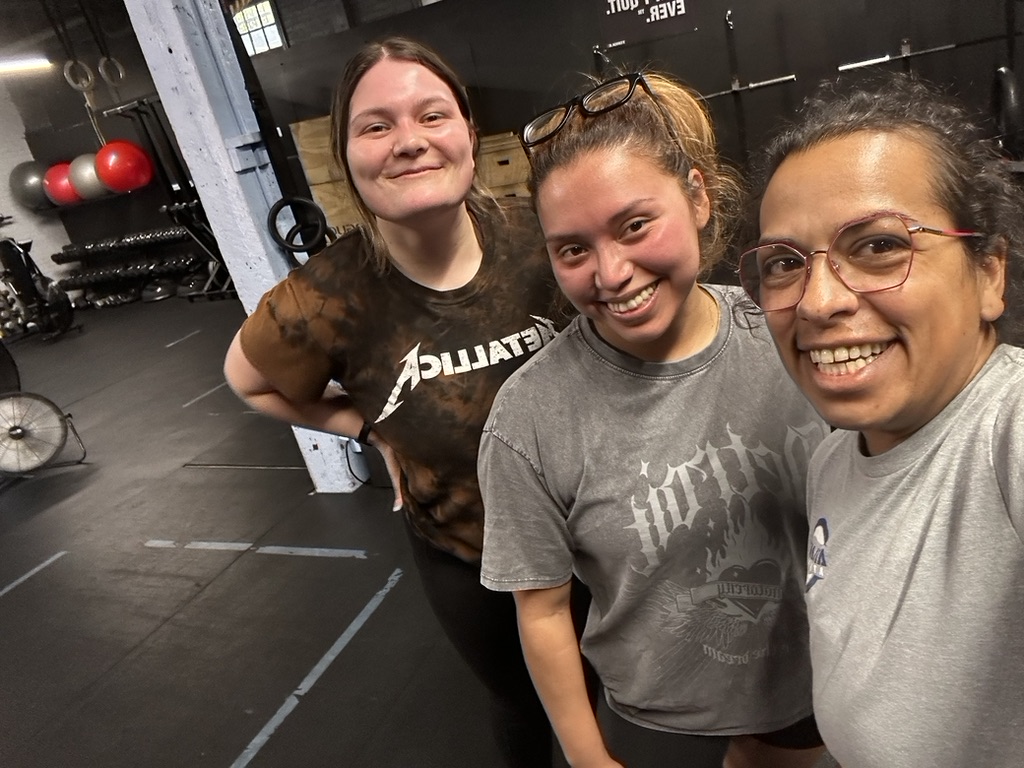 Julie Whitley smiles with two clients after a workout session in the gym, showcasing teamwork, positivity, and strength training success.